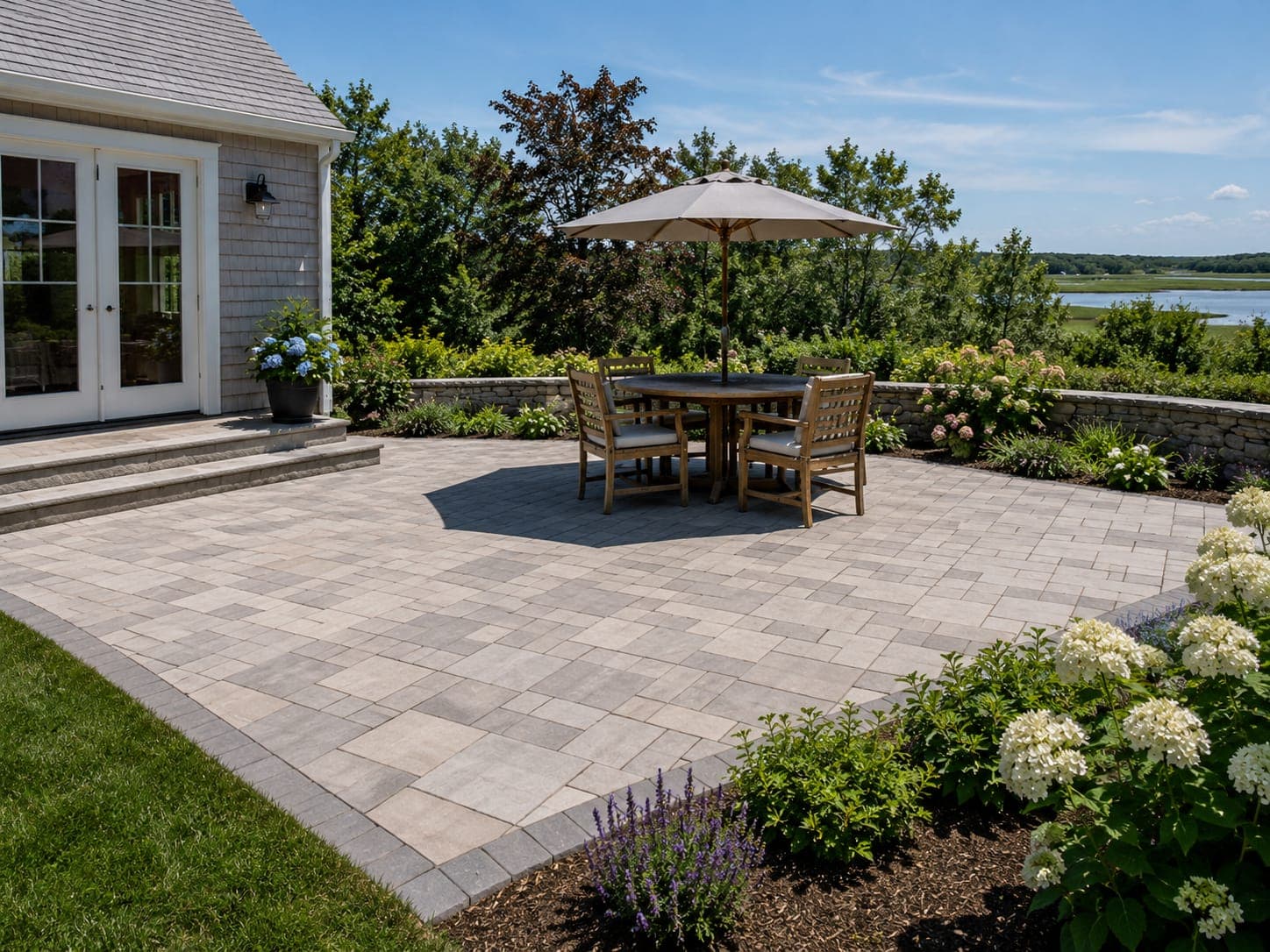 Finished gray paver patio with a soldier-course border, dining set and stone fire pit at a Cape Cod home